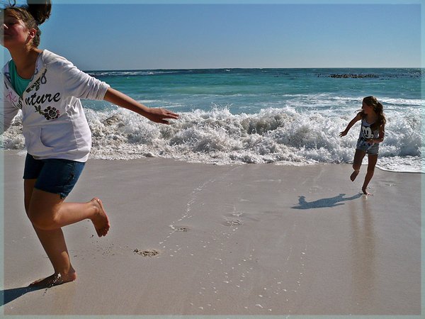 Kids running from wave on beach