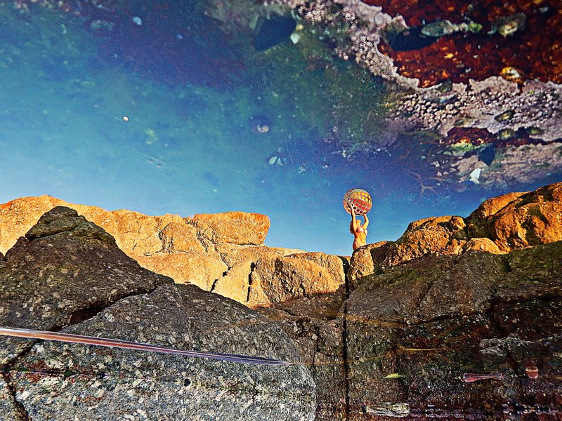 woman playing on saunders rocks reflected